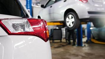 Car service - red backlights of white auto in opposite of lifted automobile video