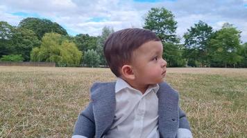 lindo bebé pequeño está posando en un parque público local de la ciudad de luton de inglaterra reino unido video