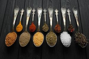 Colorful various herbs and spices for cooking on dark wooden rustic background photo