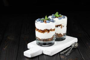 Homemade layered dessert with fresh blueberries, cream cheese or yogurt, granola on rustic background. photo