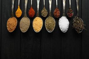 Colorful various herbs and spices for cooking on dark wooden rustic background photo