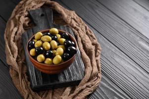 Black and green olives on a dark wooden black background. photo