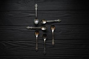 Directly above a shot of old spoons on a black table photo