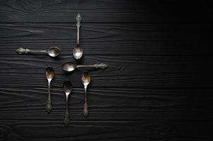 Directly above a shot of old spoons on a black table photo