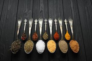 Colorful various herbs and spices for cooking on dark wooden rustic background photo