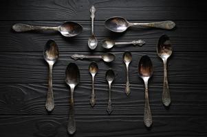 Directly above a shot of old spoons on a black table photo