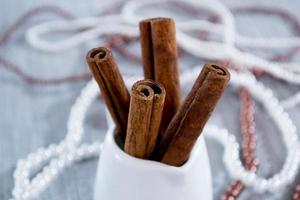 palitos de canela en un vaso blanco, cuentas sobre un fondo azul foto