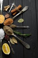 Colorful various herbs and spices for cooking on dark wooden rustic background photo