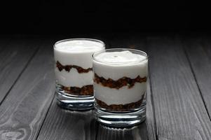 Layered dessert with granola on a wooden dark wooden background. photo