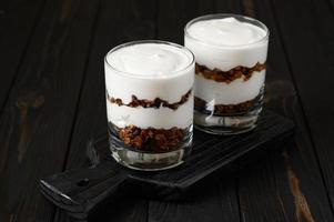 Greek yogurt with granola on a wooden dark wooden background. photo