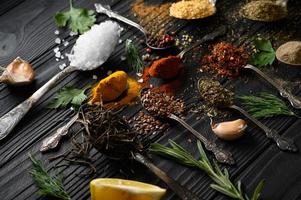 Colorful various herbs and spices for cooking on dark wooden rustic background photo