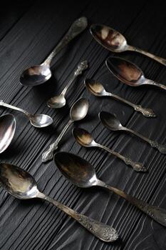 Directly above a shot of old spoons on a black table photo