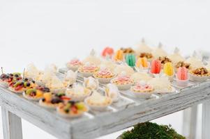 variedad de deliciosos y apetitosos postres dulces con crema, bayas y pastelería, panadería y pasteles en la gran mesa de bodas en la celebración foto