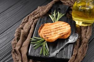 Sliced toasted bread with extra virgin olive oil and rosemary on a black background photo