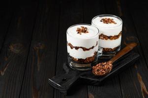Greek yogurt with granola on a wooden dark wooden background. photo