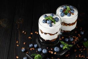 Dessert with mascarpone cheese, fresh blueberries and muesli in a glass on a rustic background. photo