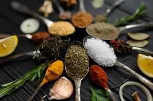 Colorful various herbs and spices for cooking on dark wooden rustic background photo