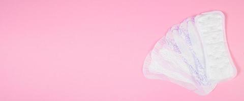 Set of sanitary pads on pink background. Daily feminine hygiene product. photo