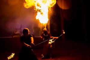 Fire show on the open air festival. Artists exhale flame, pillar of fire on a black background - July 8, 2015, Russia, Tver. photo