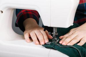 Woman tailor works on sewing machine. World tailors day. Close-up of sewing process. photo