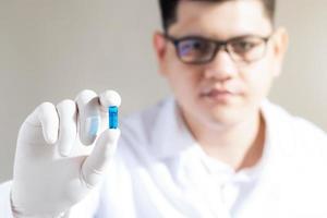 male scientist Hand holding a blue pill capsule in a pharmaceutical research laboratory, inventing and researching drugs for serious human diseases. photo