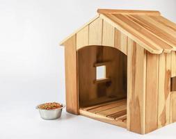 casa de perro de madera vacía con plato de comida para perros sobre fondo blanco. aislado. foto