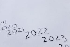 figures and the date of 2022 drawn on the snow photo