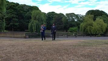 2 jeunes hommes asiatiques posent avec un bébé garçon au parc public local de luton england uk video