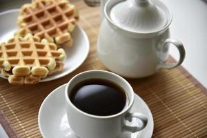 pareja de té con gofres vieneses en una alfombra. fiesta de té con gofres. una taza y plato de porcelana sobre una estera. foto