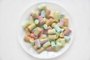 Colorful sweet marshmallows on a white plate. Delicious marshmallows for coffee. photo