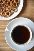 A teapot with tea and a cup with a saucer and pretzels are salty. photo