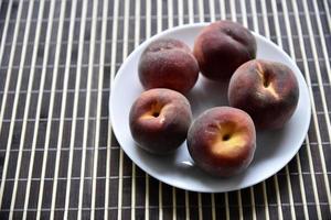 Juicy red and yellow peaches on a white plate. Delicious peaches for lunch. photo