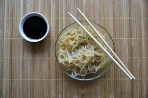 Korean rice noodles with meat and spices in a glass bowl. Delicious noodles with meat and spices. Korean noodle sticks.
