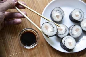 tomado con palillos sushi con atún para comer. rollo de pescado delicioso. rollo de sushi de arroz en una alfombra. foto