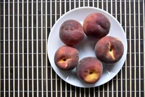 jugosos melocotones rojos y amarillos en un plato blanco. deliciosos melocotones para el almuerzo. foto