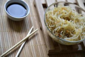 Korean rice noodles with meat and spices in a glass bowl. Delicious noodles with meat and spices. Korean noodle sticks. photo