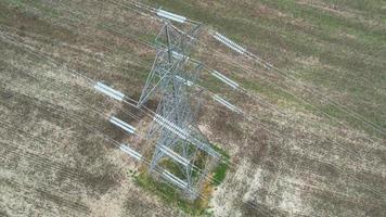 postes de suministro de energía de alto voltaje con cables que recorren las tierras de cultivo y el campo británicos, vista aérea de ángulo alto por la cámara de drones video