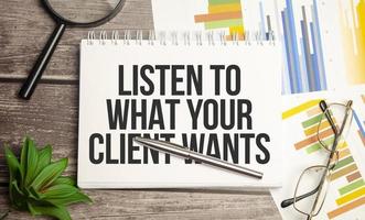 Text LISTEN TO WHAT YOUR CLIENT WANTS on a notepad with magnifier , glasses and pen photo