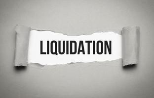 liquidation word on white torn paper. bankruptcy concept photo