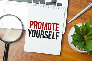 PROMOTE YOURSELF writing text post it paper in office on laptop computer keyboard photo