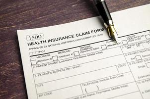 health insurance form with pen on wooden background photo