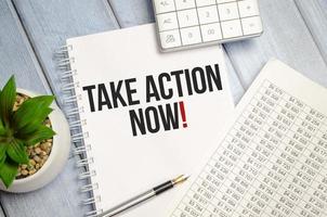 take action Now words on notebook closeup photo