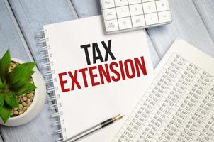 TAX EXTENSION text on paper with calculator, notepad and charts photo