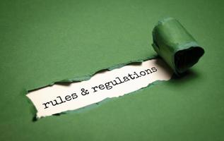 palabra de reglas y regulaciones bajo papel verde rasgado foto