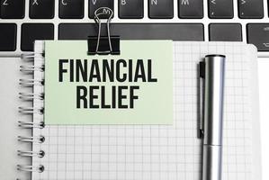 Financial Relief text in notepad on laptop keyboard photo