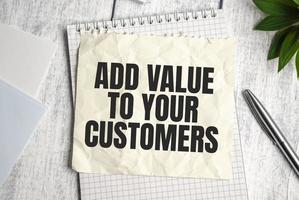 ADD VALUE TO YOUR CUSTOMERS note on wooden background and pen photo
