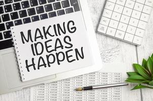 making ideas happen text on notepad and laptop on wooden background photo