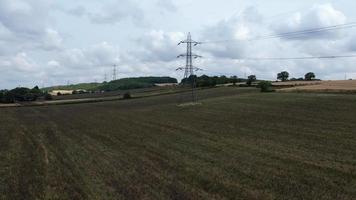 High Voltage Power Supply Poles with Cables Running Through British Farmlands and Countryside, Aerial high angle view by drone's camera video