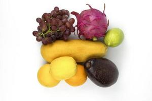 Healthy red and yellow fruits, grapes, papaya, avocado, orange isolated on white background photo