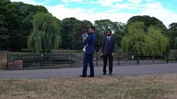 2 jeunes hommes asiatiques posent avec un bébé garçon au parc public local de luton england uk video